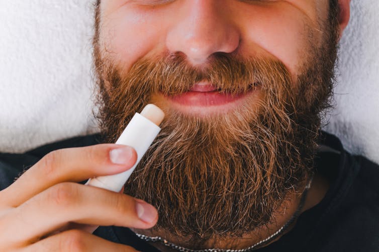 Man with beard applying lip balm