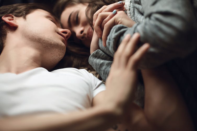 A young couple lying in bed together.