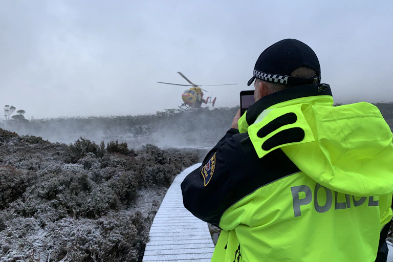 Police officer looks at a helicopter on a wintery trail