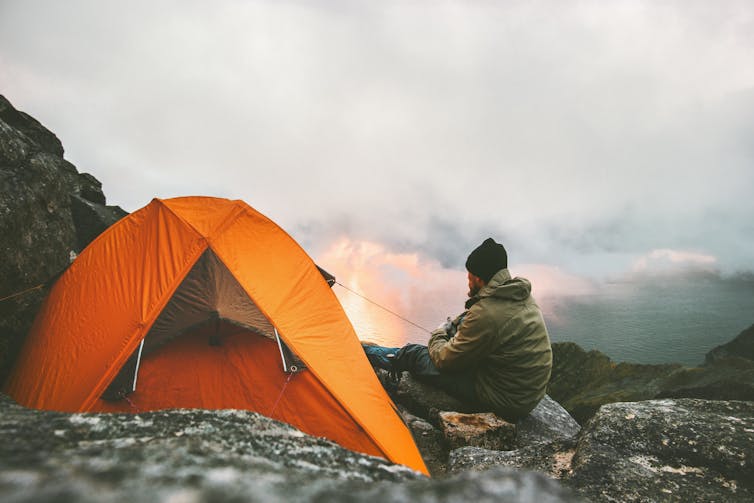 Hiker beside an orange tent