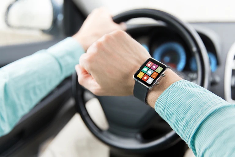 un homme porte une montre intelligente tandis qu'il conduit une voiture