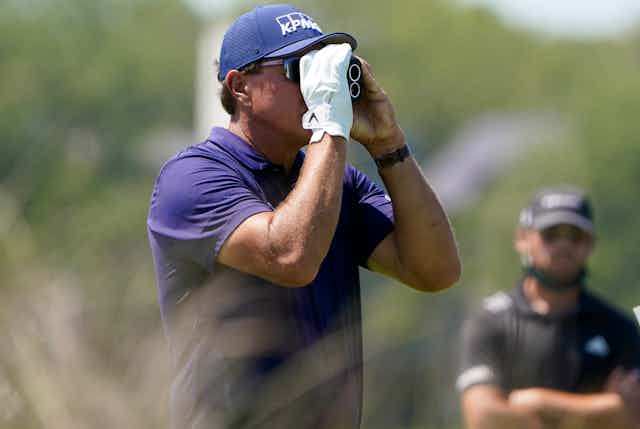 Golfer looks through range finder.