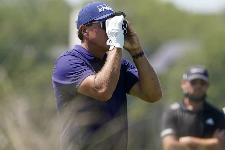 Golfer looks through range finder.