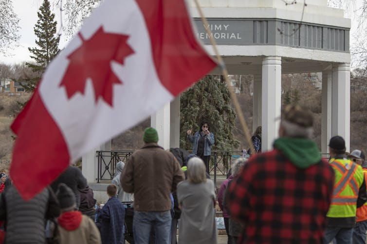 Man stands holding upside down Canada flag at 'freedom' rally in Saskatchewan