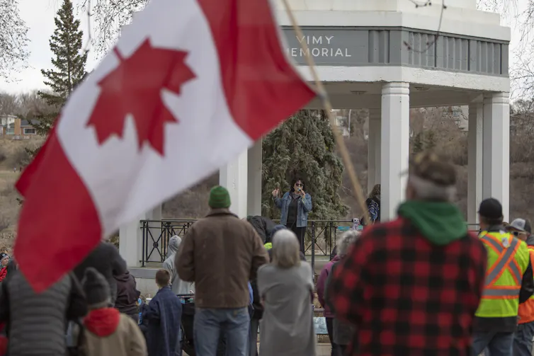 Man stands holding upside down Canada flag at 'freedom' rally in Saskatchewan