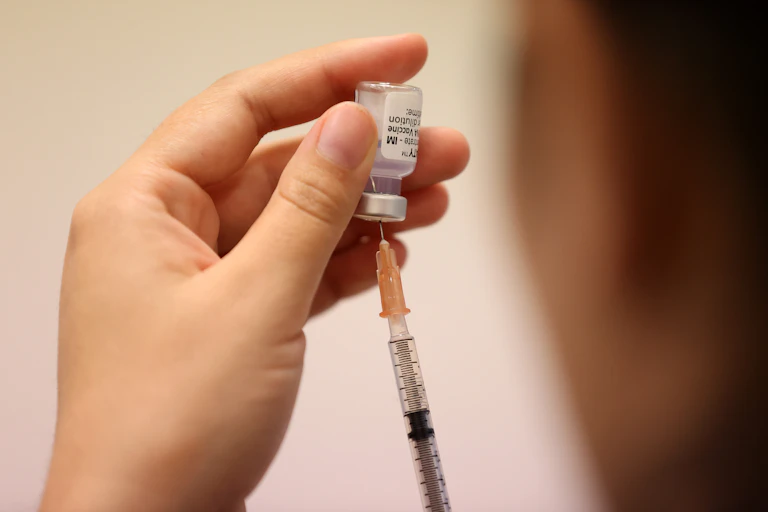 hand holding vaccine vial and syringe