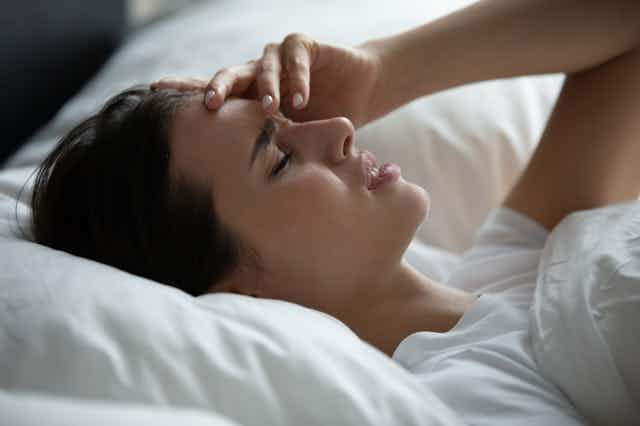 Woman lying in bed headache