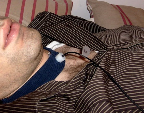 Close-up of a man's neck with a band holding a small microphone to his throat