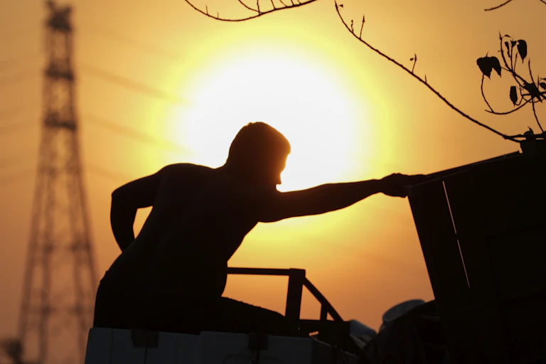 A silhouette of a man loading goods onto a truck at sunset.