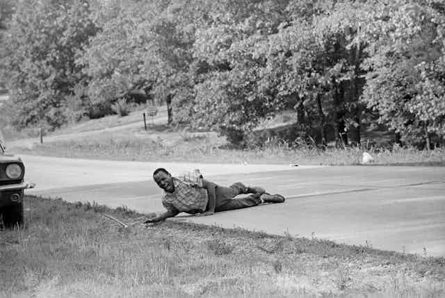 James Meredith, shouting with pain as he pulling himself across the street after being shot