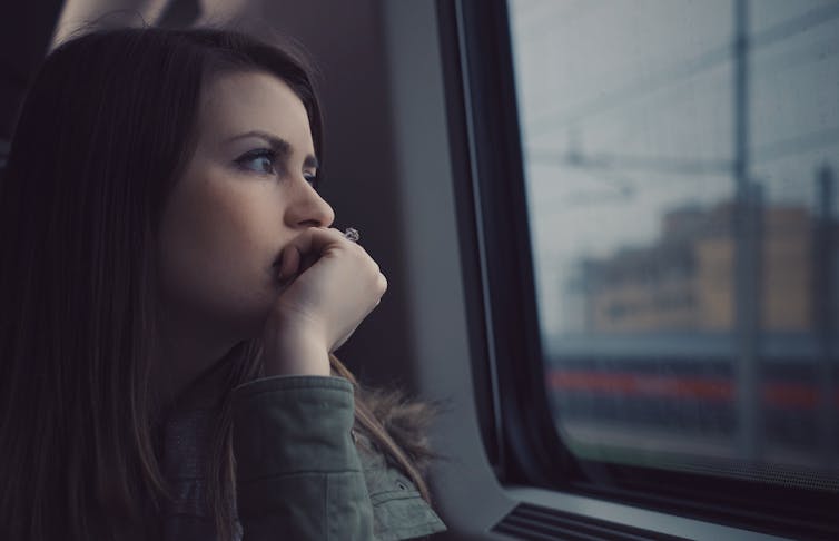 A woman gazes out of a commuter vehicle window.