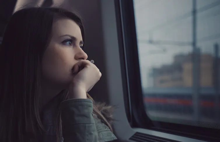 A woman gazes out of a commuter vehicle window.