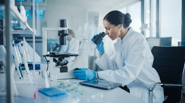 Une femme regarde des échantillons sous un microscope dans une laboratoire de recherche médical
