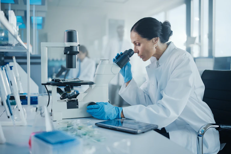 Une femme regarde des échantillons sous un microscope dans une laboratoire de recherche médical