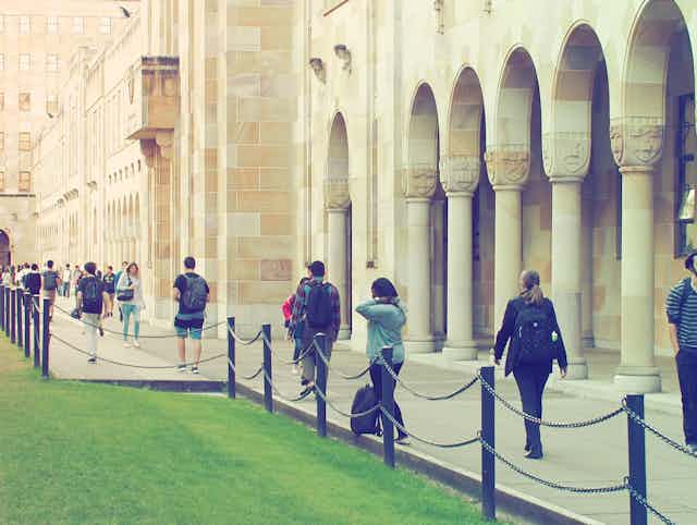 people walking in front of sandstone university buildings