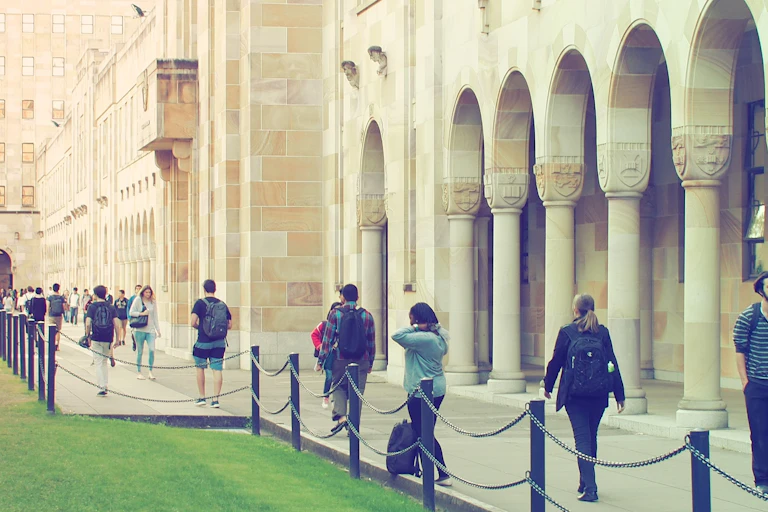 people walking in front of sandstone university buildings