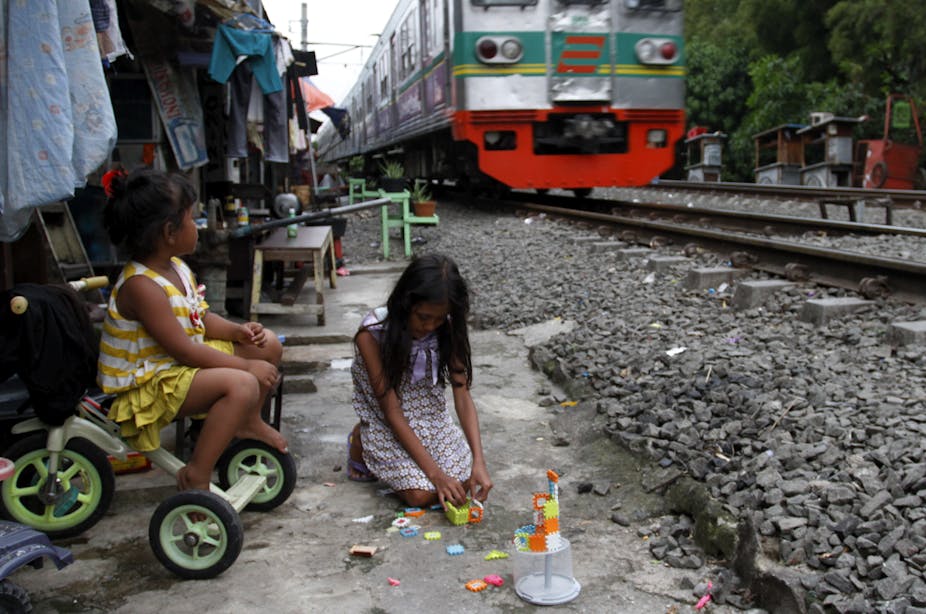 Dua orang anak bermain di pinggir rel kereta api.