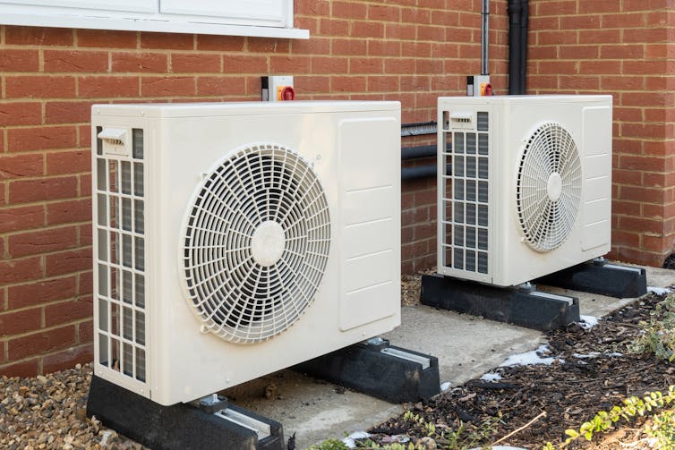 Two large white units with central fans outside a house.