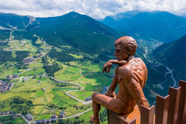 Statue looking over large mountain meadow and valley