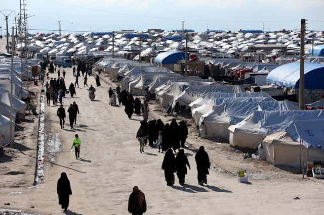 A long view of the al-Hol displacement camp in Syria, where people are walking between tents. 