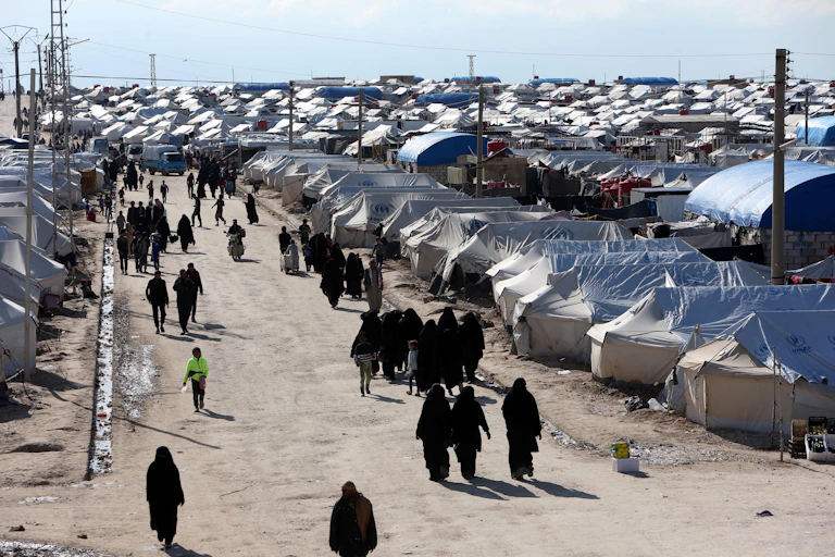 A long view of the al-Hol displacement camp in Syria, where people are walking between tents.