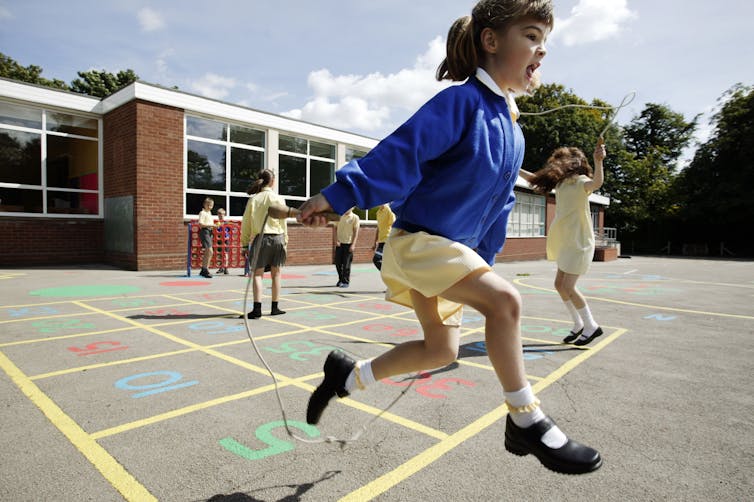 A primary school girl skips in the playground
