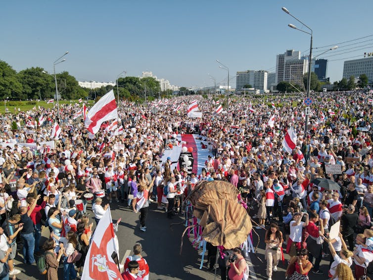 Huge crowds waving red-and-white flags in a public square