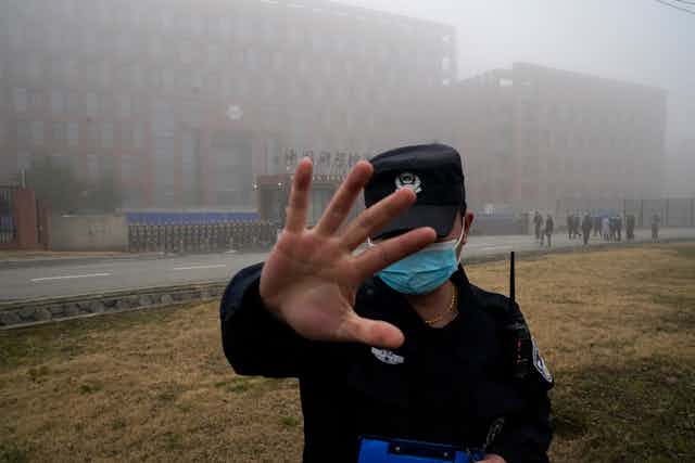 Security guard raises his hand to prevent people from entering the security perimeter of the Wuhan Institute of Virology (WIV)