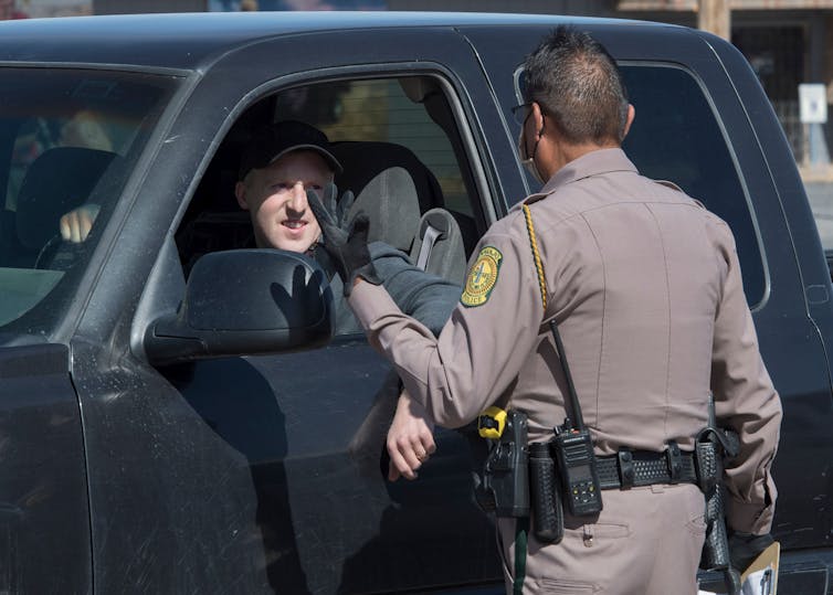 A police officer talks to a man driving a vehicle
