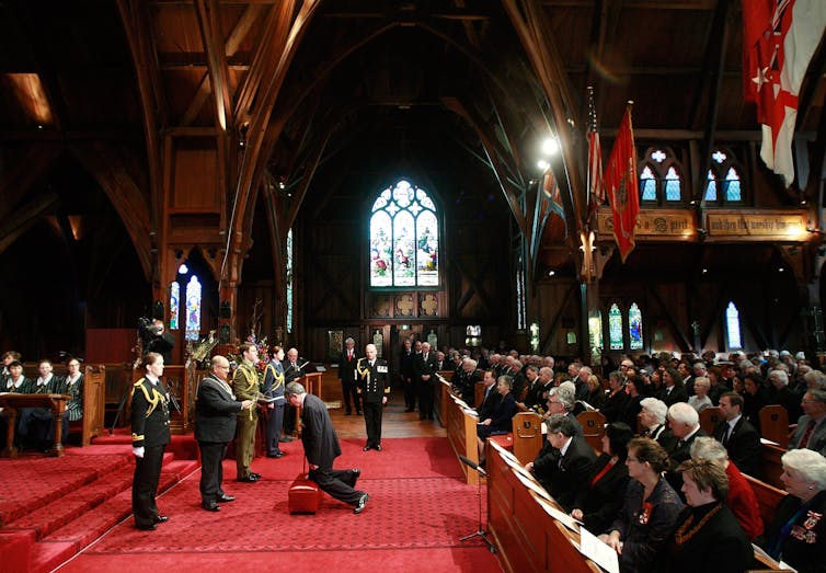 Man kneeling to be knighted inside a church