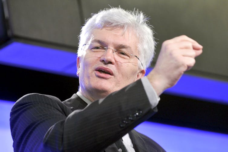 Man in suit gestures during a speech