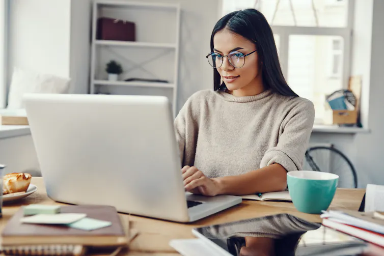 A woman working from a laptop in her home.