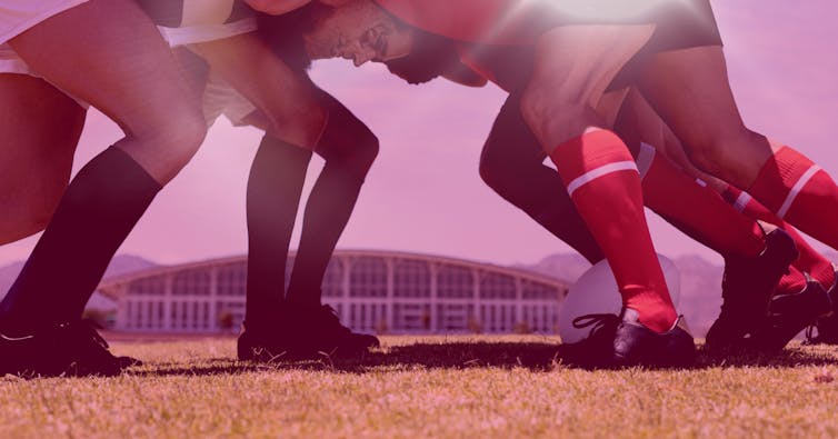 Rugby players in a scrum with stadium in the background