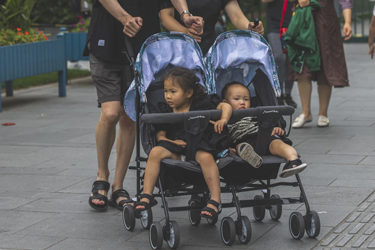 A couple in Shanghai pushes a double stroller with two small children in it.