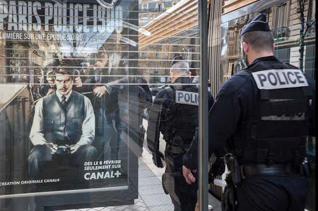 Police walk past a bus shelter with an add for a police cop show