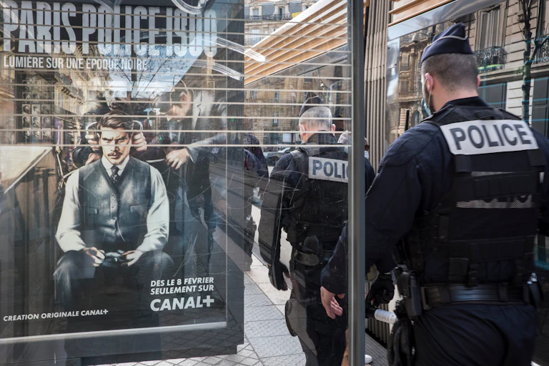 Police walk past a bus shelter with an add for a police cop show
