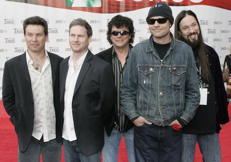Members of The Tragically Hip, including Gord Downie in a toque and sunglasses, pose for photographers on the red carpet