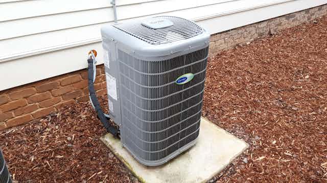 Air source heat pump on a concrete pad outside a home.