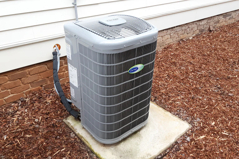 Air source heat pump on a concrete pad outside a home.