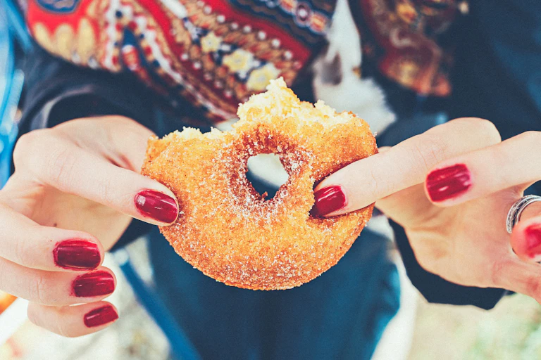 A woman holds a half-eaten donut.