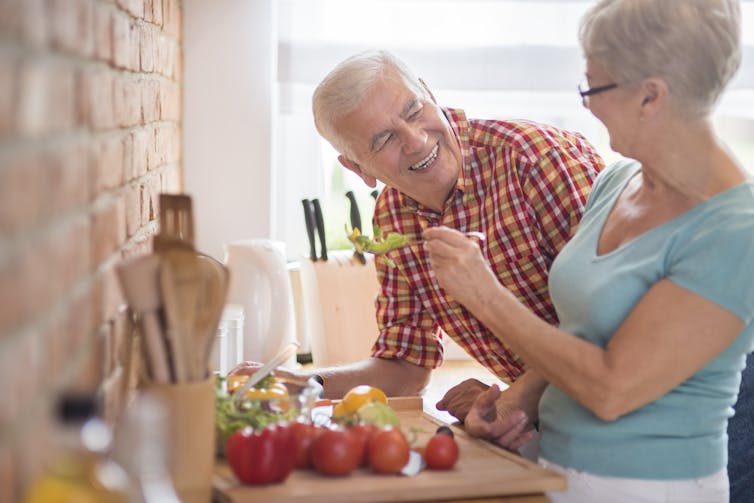 An older couple preparing vegetables in the kitchen.