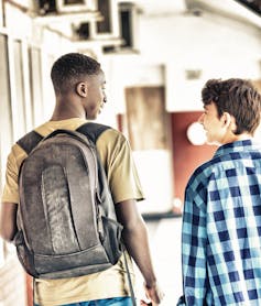 Two boys walking in a school corridor.