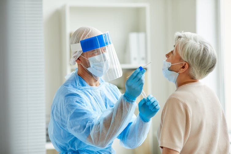 A health-care worker performs a COVID swab test on a patient.