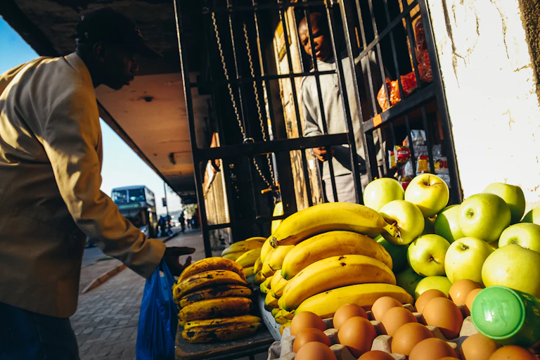 Customer at a pavement stall where fruit and eggs are on display
