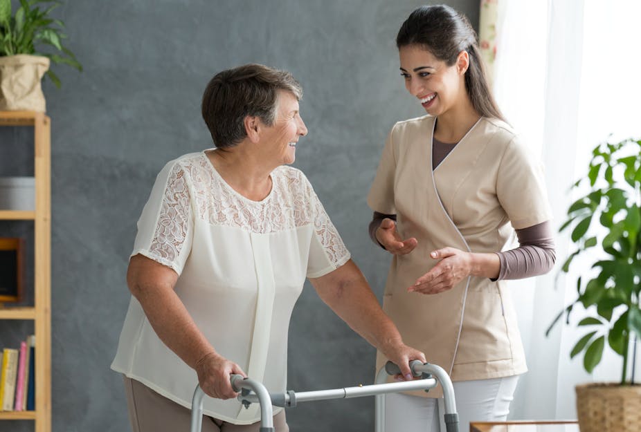 A woman standing with a zimmer frame next to a woman in scrubs.