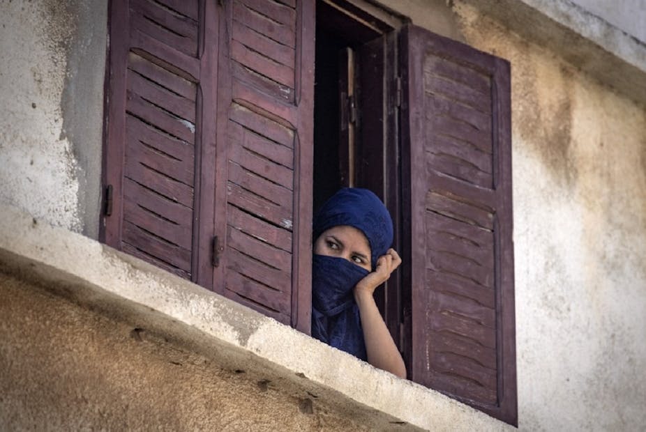 Une femme de la ville de Safi jette un œil dans la rue, pendant le confinement total de juin 2020.