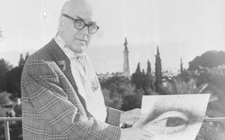 Man in glasses stands with a close up image of Mona Lisa's eye.