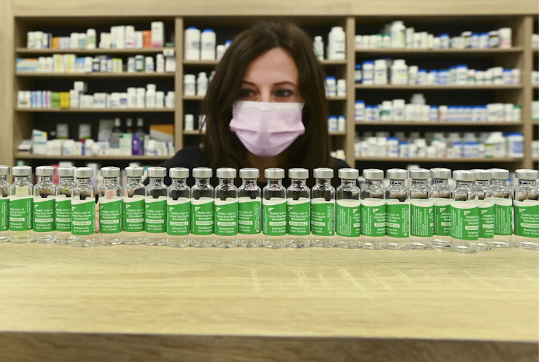 Une femme portant un masque examine des fioles