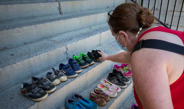 A person touches children's shoes on concrete steps.