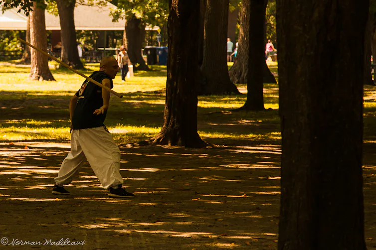 a man tosses a stick in the air and catches it behind his back